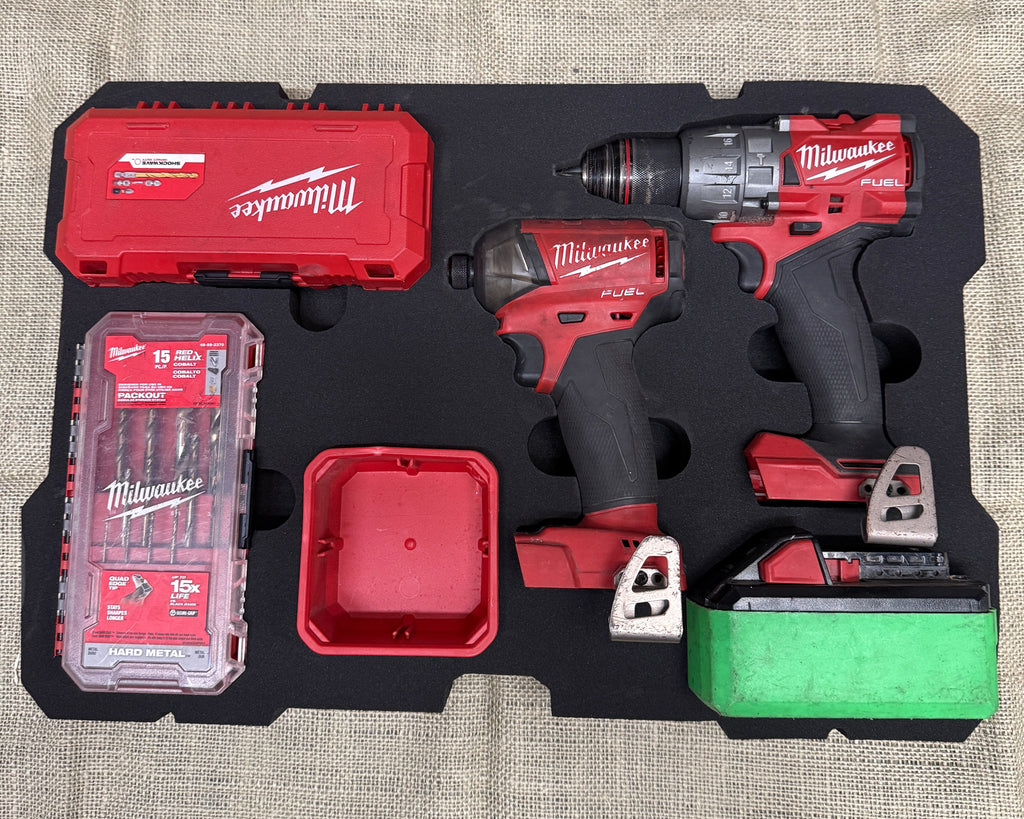 Milwaukee tool set with drill, impact wrench, and accessories on a textured surface