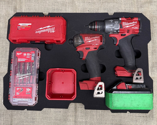 Milwaukee tool set with drill, impact wrench, and accessories on a textured surface